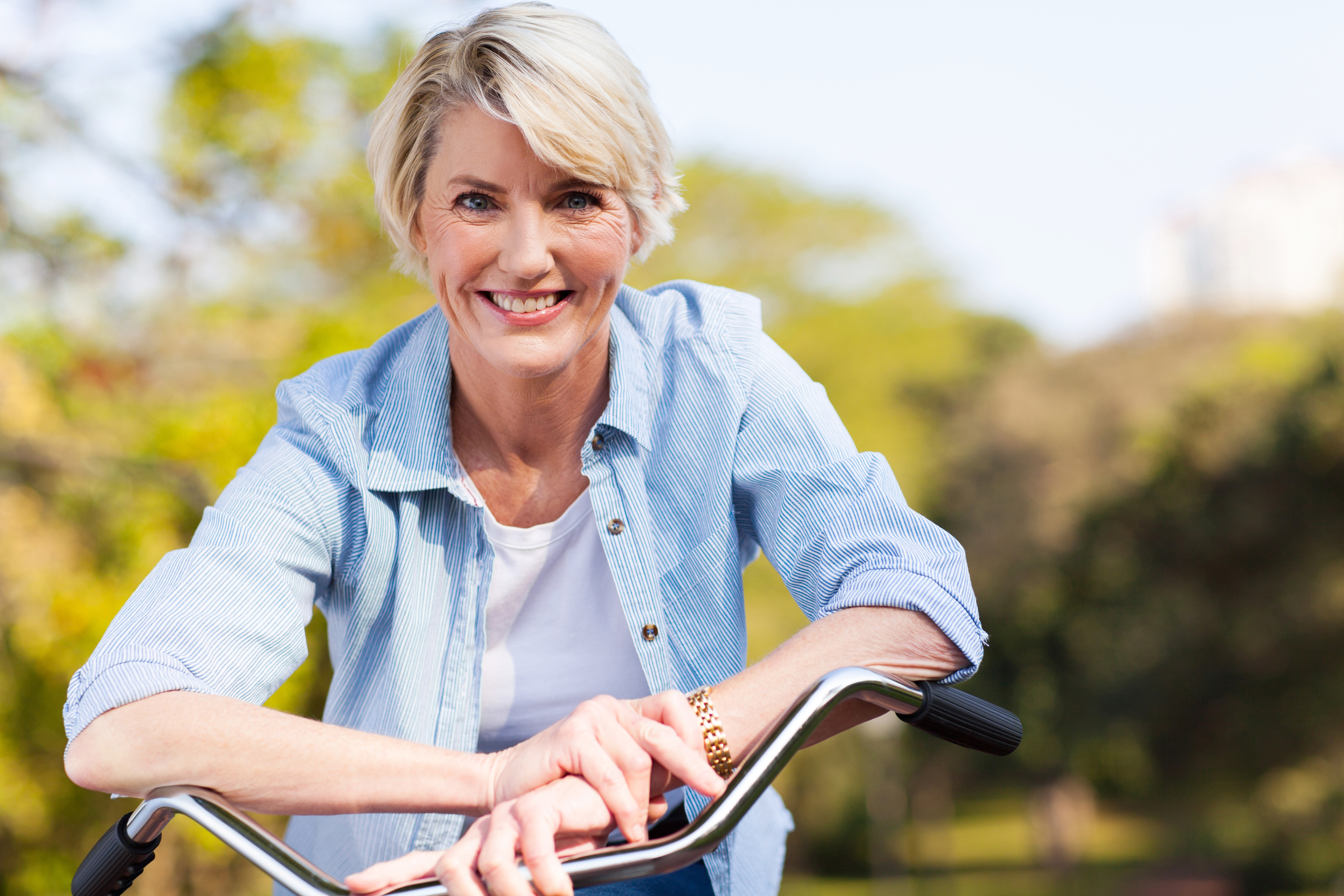 An older woman poses over the handlebars of a bike