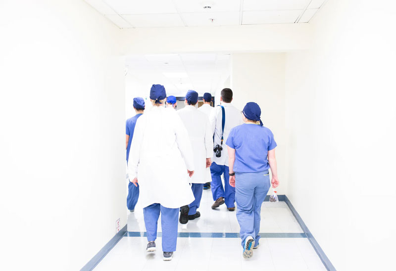 A group of healthcare professionals walk down a white hallway.