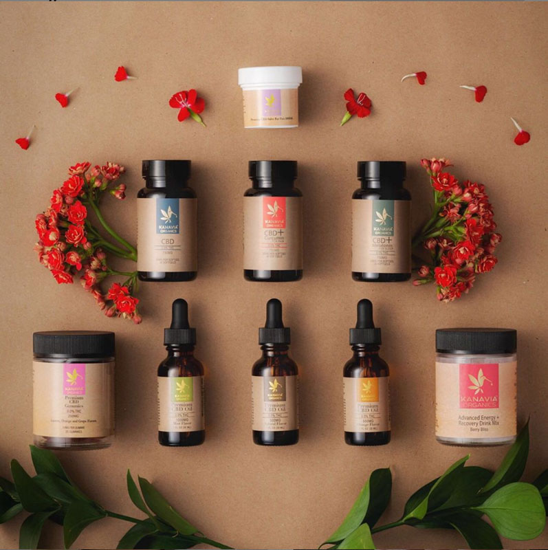 A selection of Kanavia’s organic CBD products arranged near some flowers.