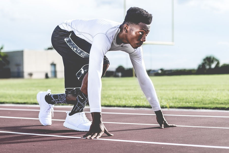 A man on an outdoor running track, in the starting position.