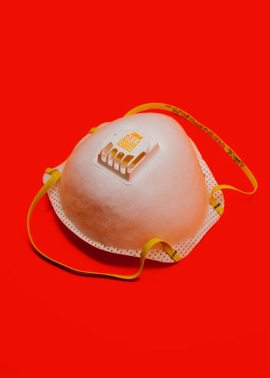 A PPE N95 mask against a red background.