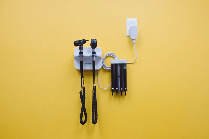 Medical professional tools hang on a bright yellow wall.