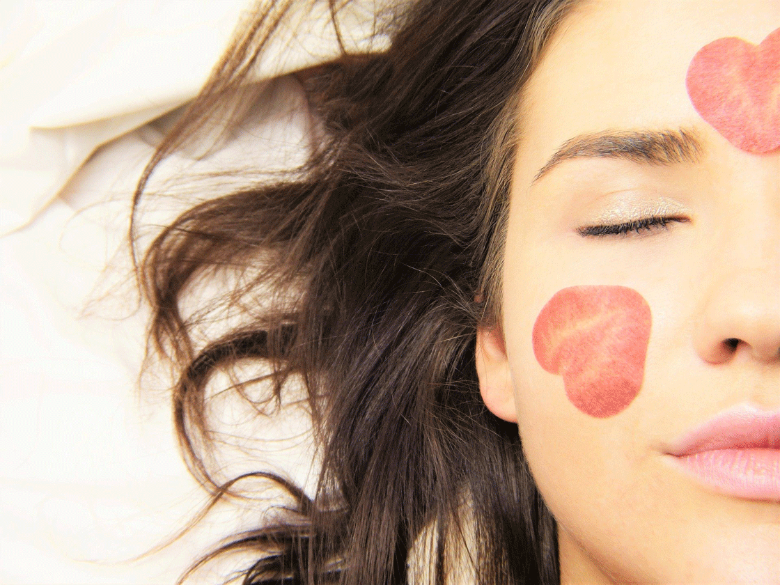 One side of a woman’s face with strawberry slices on the skin