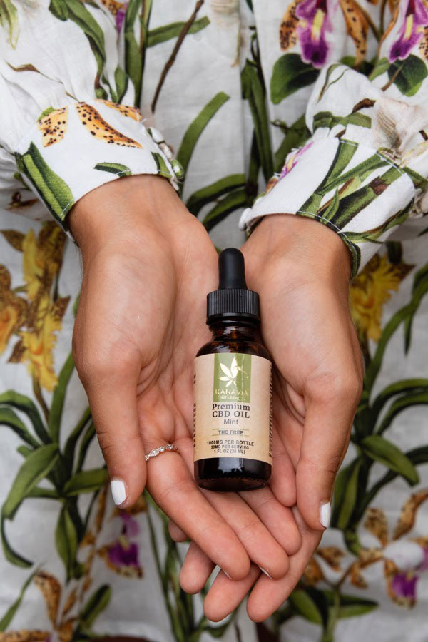 Woman in floral dress holding Kanavia Organics Mint CBD oil in the palm of her hands