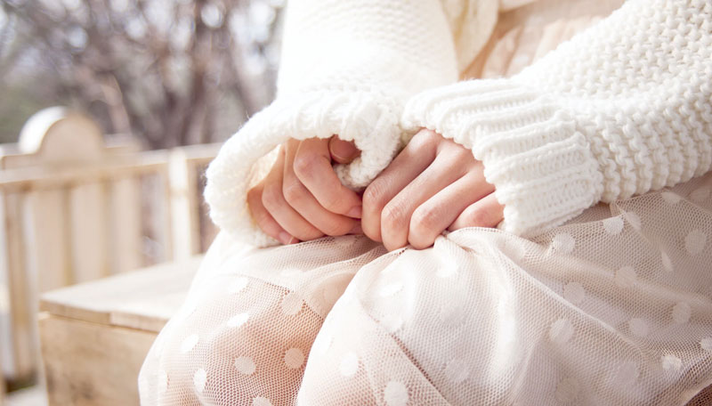 A stressed woman in all white clutches at her skirt.